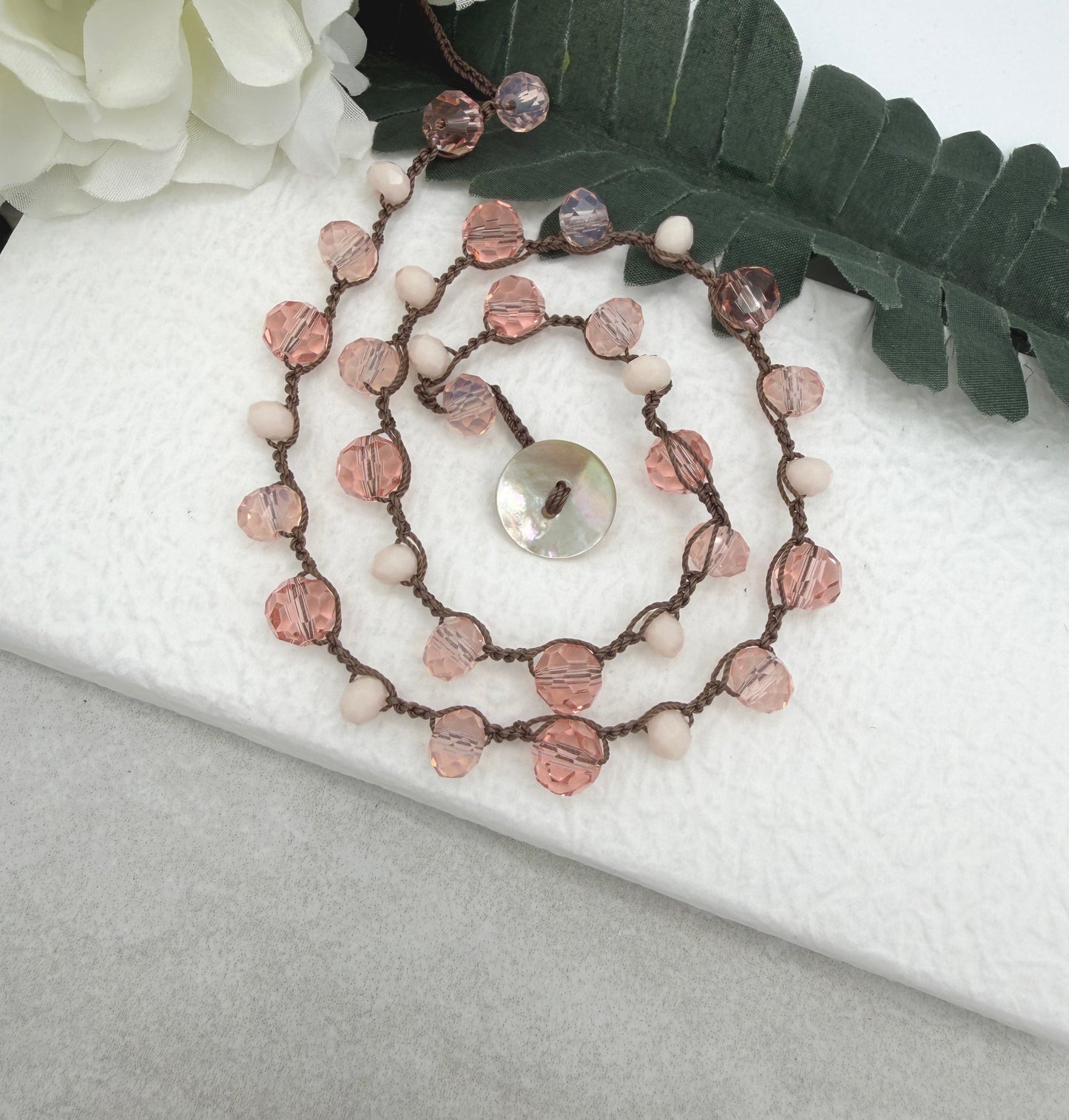 A Crocheted Necklace with a Brown Cord With Pink, Peach and Cream Crystal Beads SN-690