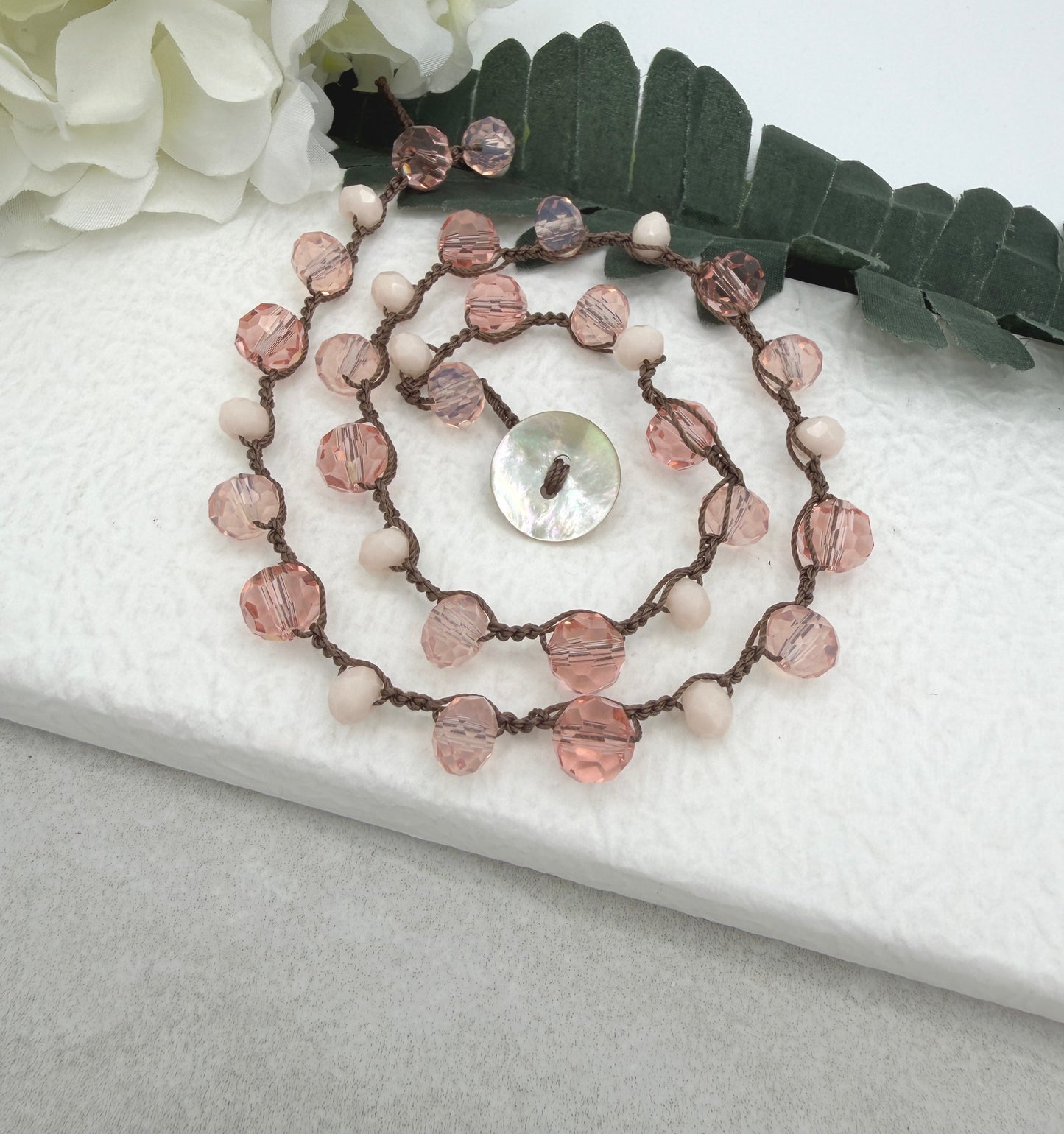 A Crocheted Necklace with a Brown Cord With Pink, Peach and Cream Crystal Beads SN-690