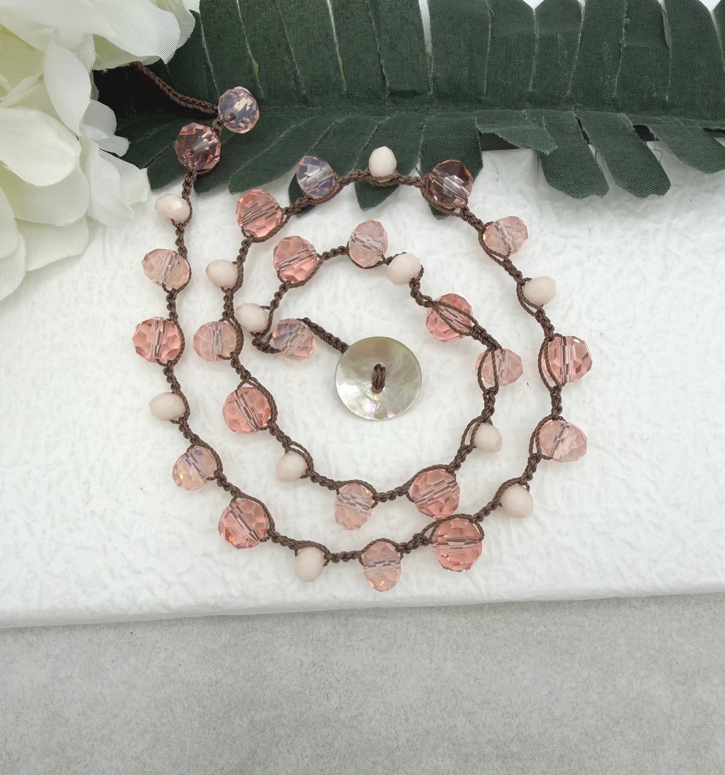 A Crocheted Necklace with a Brown Cord With Pink, Peach and Cream Crystal Beads SN-690
