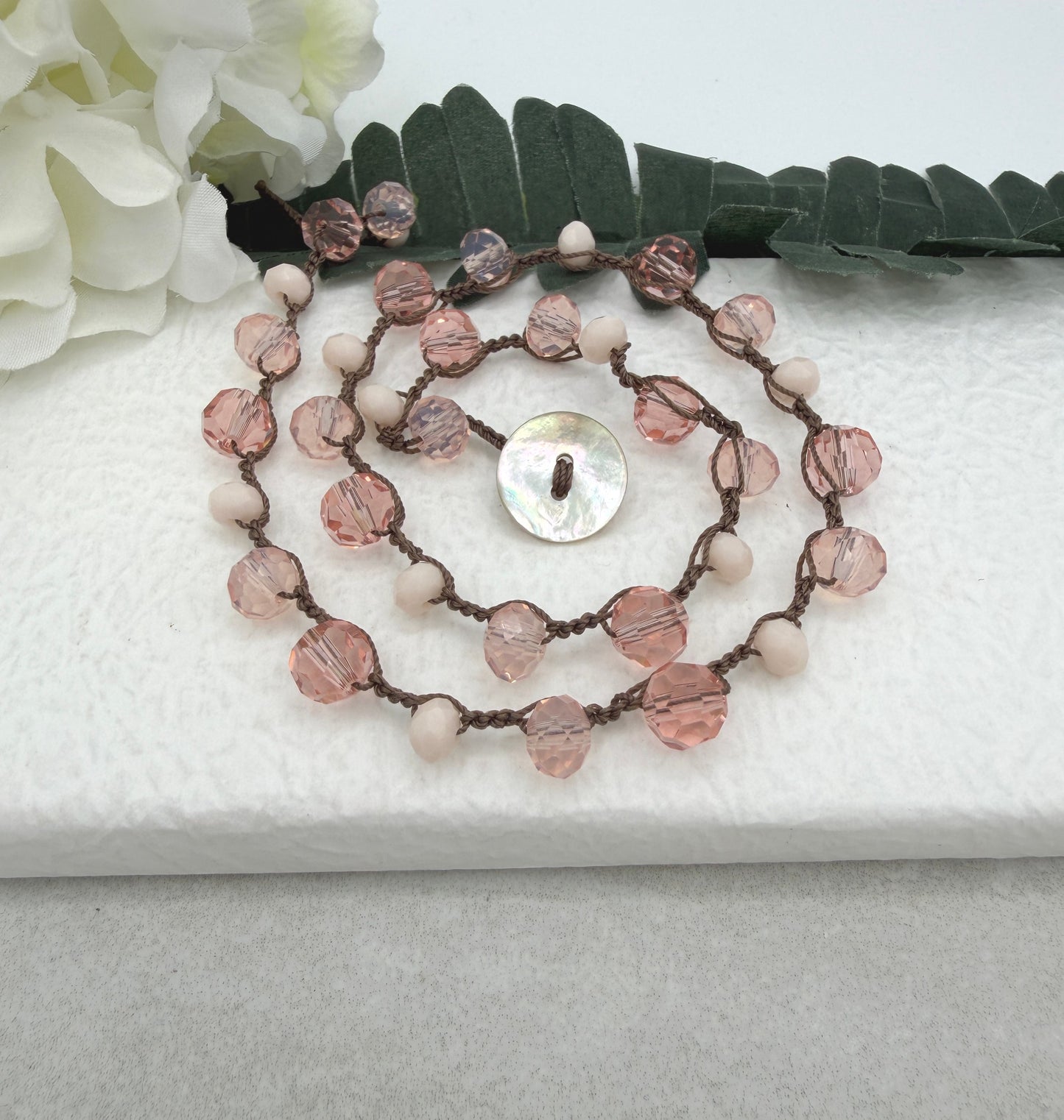 A Crocheted Necklace with a Brown Cord With Pink, Peach and Cream Crystal Beads SN-690