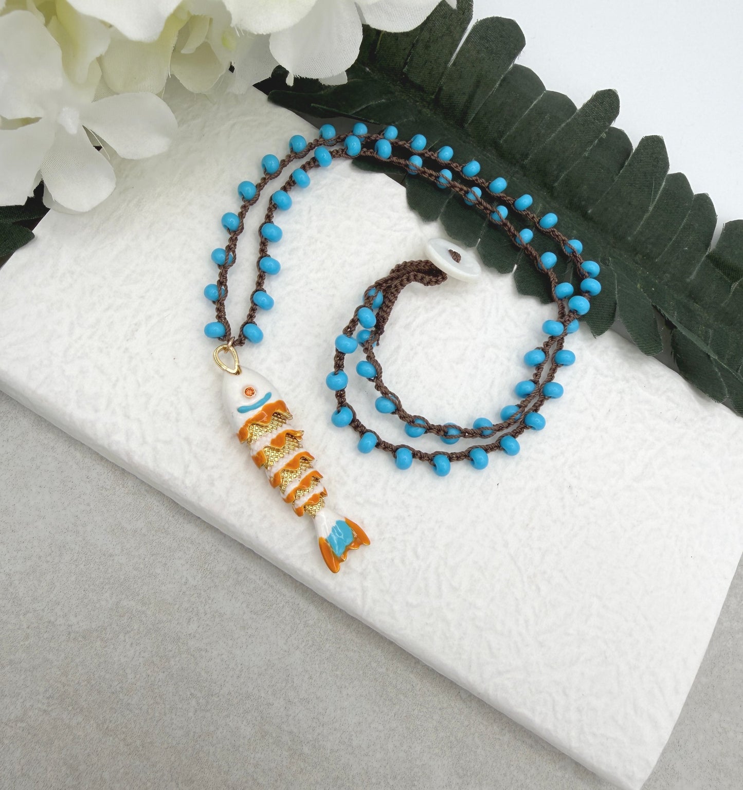 Crocheted Necklace with a Brown Cord, Turquoise Glass Beads and a White, Orangle Enameled Fish Charm SN-705
