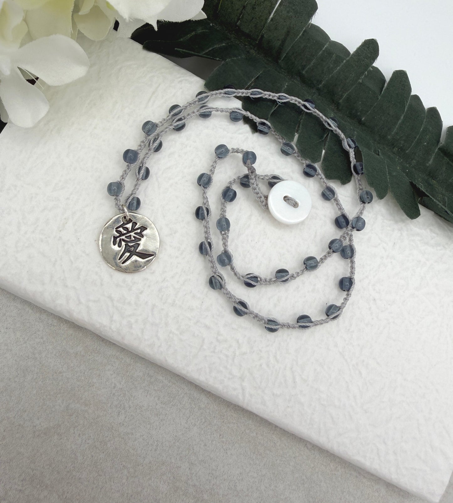 Crocheted Necklace with a Light Gray Cord, Montana Blue Glass Beads and a Round, PMC Pendant with the Symbol for Love SN-708