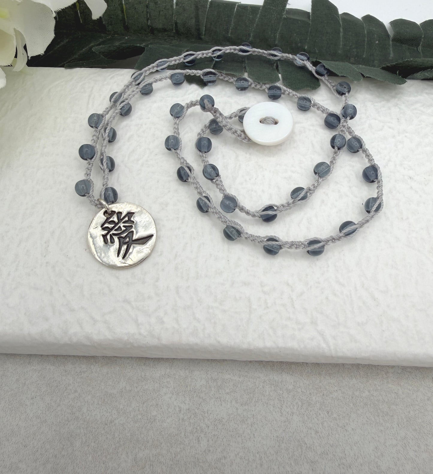 Crocheted Necklace with a Light Gray Cord, Montana Blue Glass Beads and a Round, PMC Pendant with the Symbol for Love SN-708
