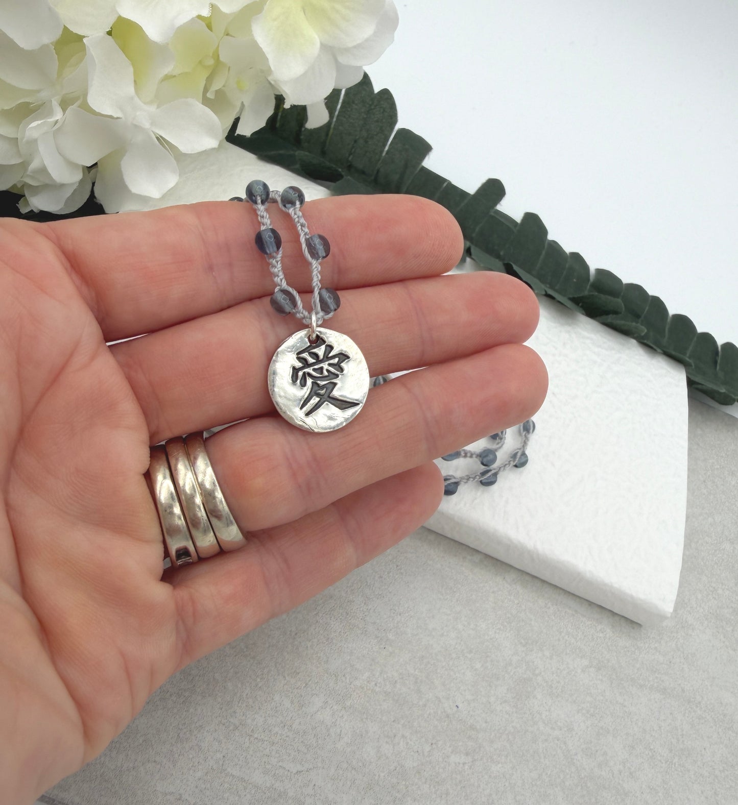 Crocheted Necklace with a Light Gray Cord, Montana Blue Glass Beads and a Round, PMC Pendant with the Symbol for Love SN-708
