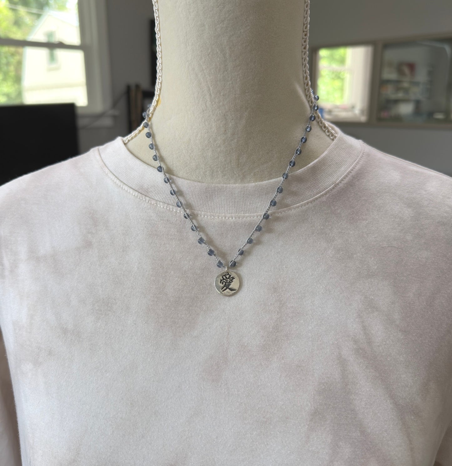 Crocheted Necklace with a Light Gray Cord, Montana Blue Glass Beads and a Round, PMC Pendant with the Symbol for Love SN-708