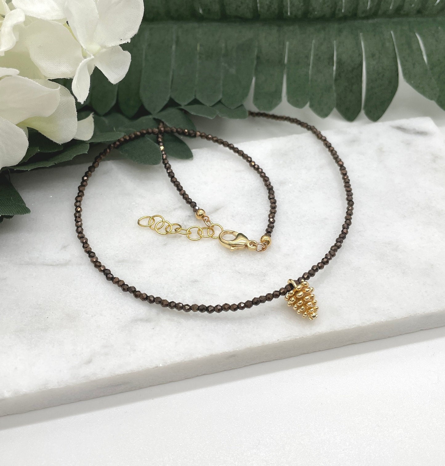 Necklace with Tiny Brown Crystal Beads and a Gold Plated Pinecone Charm GCDN-158
