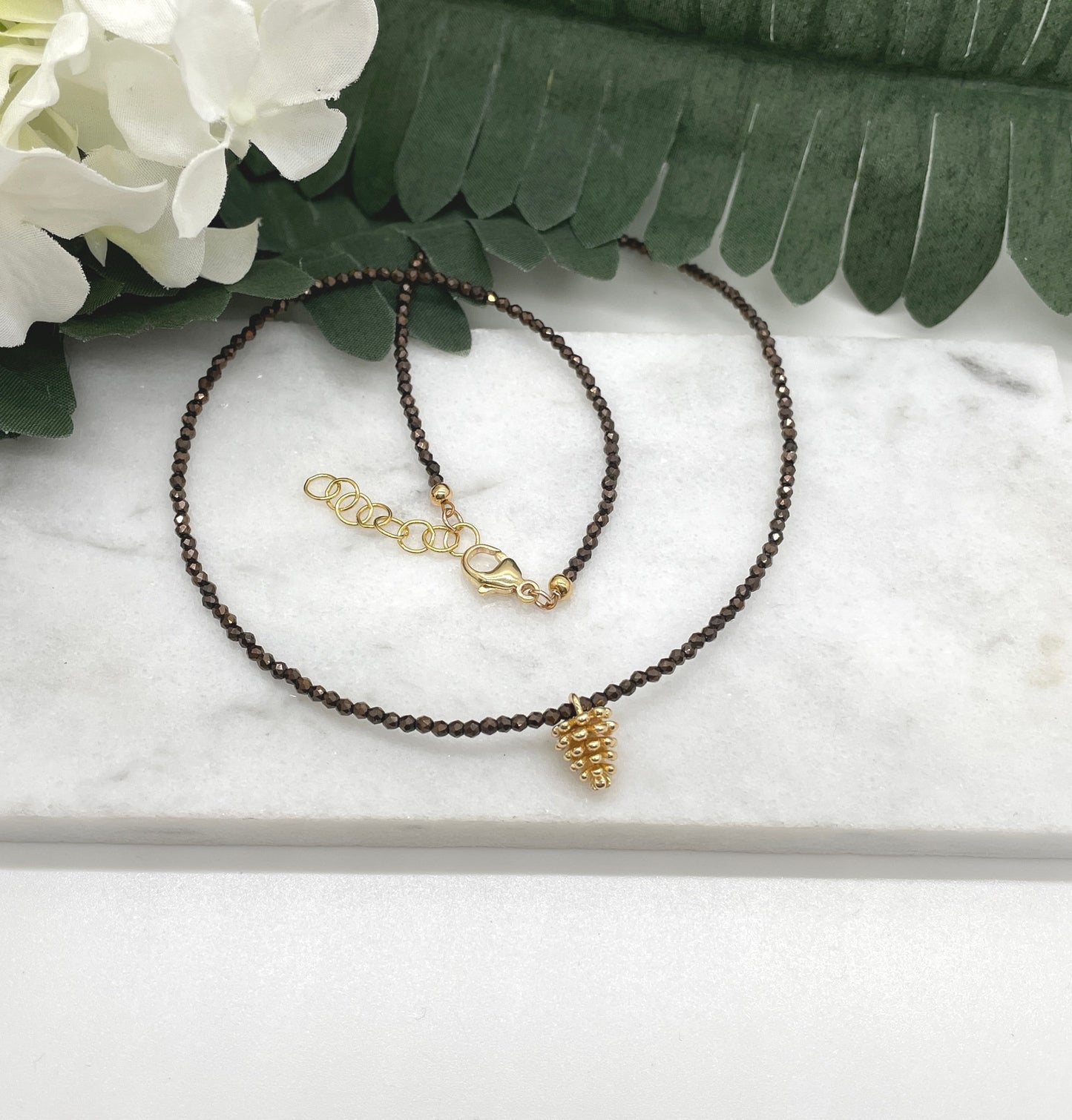 Necklace with Tiny Brown Crystal Beads and a Gold Plated Pinecone Charm GCDN-158