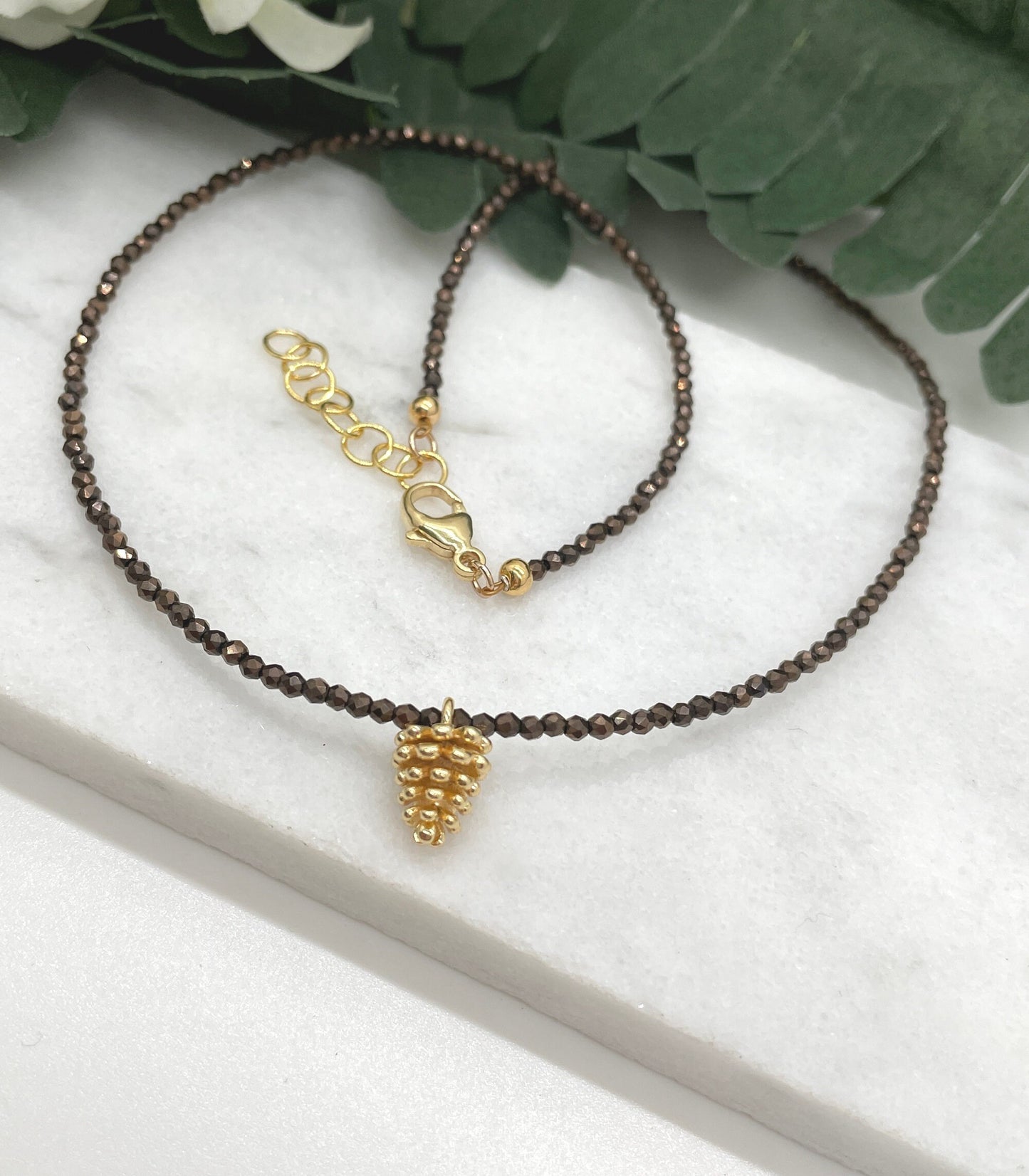 Necklace with Tiny Brown Crystal Beads and a Gold Plated Pinecone Charm GCDN-158