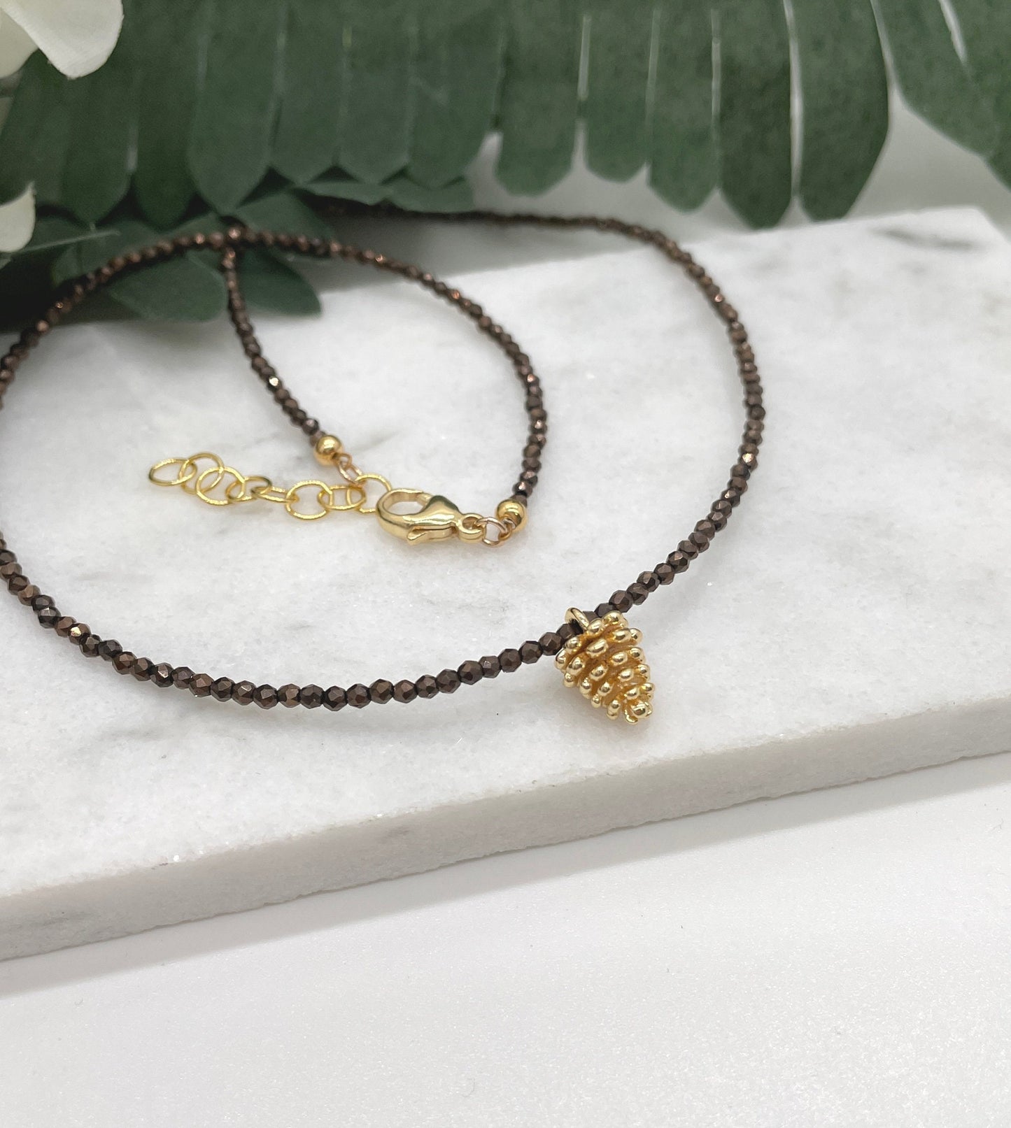 Necklace with Tiny Brown Crystal Beads and a Gold Plated Pinecone Charm GCDN-158