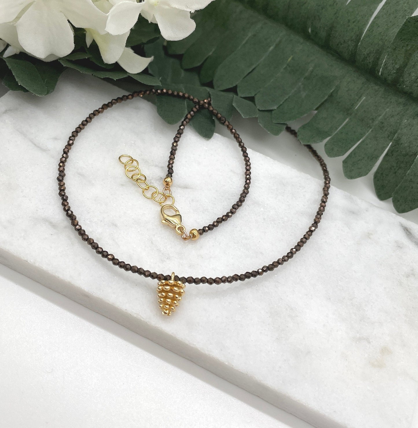 Necklace with Tiny Brown Crystal Beads and a Gold Plated Pinecone Charm GCDN-158
